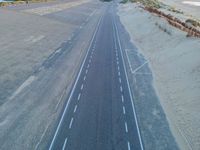 an aerial view of a roadway on a beach side highway that is paved with white lines