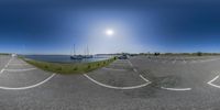 two cars parked in a lot next to the water with an ocean and sun behind