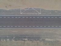 a bird's eye view of an empty city road next to a sand mountain