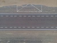 a bird's eye view of an empty city road next to a sand mountain