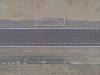 a bird's eye view of an empty city road next to a sand mountain