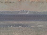 a bird's eye view of an empty city road next to a sand mountain