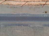 a bird's eye view of an empty city road next to a sand mountain