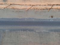 a bird's eye view of an empty city road next to a sand mountain