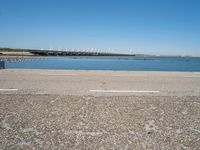 a paved parking lot next to the ocean and some buildings on a blue sky day