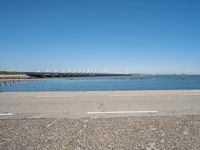 a paved parking lot next to the ocean and some buildings on a blue sky day