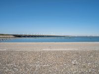 a paved parking lot next to the ocean and some buildings on a blue sky day