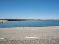 a paved parking lot next to the ocean and some buildings on a blue sky day