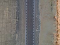 two airplanes on an empty runway from above in the desert, with a line of white lines