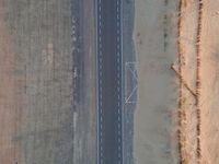 two airplanes on an empty runway from above in the desert, with a line of white lines