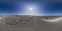 360 lens photo of street traffic with sun in sky above them and road ahead in foreground