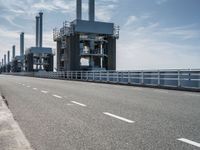 a man riding a bicycle on a road next to a sea view and industrial area