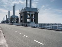 a man riding a bicycle on a road next to a sea view and industrial area