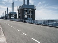 a man riding a bicycle on a road next to a sea view and industrial area