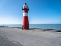 a lighthouse on a pier by the ocean on a sunny day with clear skies overhead