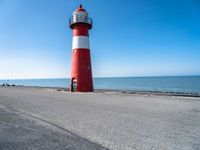 a lighthouse on a pier by the ocean on a sunny day with clear skies overhead