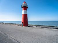 a lighthouse on a pier by the ocean on a sunny day with clear skies overhead