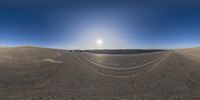 the wide angle view of two vehicles driving down an empty road with an icy sun behind them