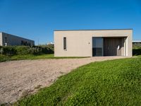 an empty concrete structure sitting in grass and gravel next to a beach house on the sand