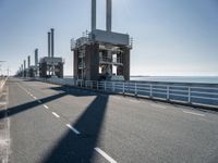 an empty street lined with power stations and wind turbines in the distance, in the afternoon