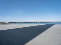 a long concrete walkway with a parking spot and pier in the background, as if on a boat