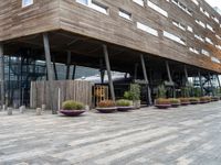 a photo of a building made of wooden and concrete with different planters on the side