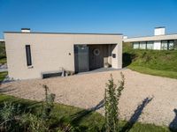 a house made of clay and gravel with its driveway and entry open to the patio