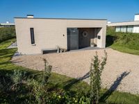 a house made of clay and gravel with its driveway and entry open to the patio