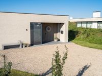 a house made of clay and gravel with its driveway and entry open to the patio