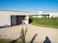 a house made of clay and gravel with its driveway and entry open to the patio