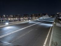 a car is driving down the street at night, by a bridge with traffic lights on