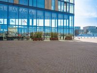 a parking area of people walking next to tall buildings and glass windows on the outside