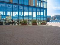 a parking area of people walking next to tall buildings and glass windows on the outside