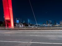 a freeway is running at night with a red light in the city behind it, and cars