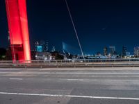 a freeway is running at night with a red light in the city behind it, and cars