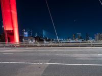 a freeway is running at night with a red light in the city behind it, and cars