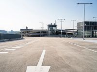 white arrows are shown on the parking lot of an airport in the day time, with three light poles and three light pole poles