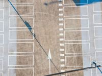 an overhead shot shows the pavement and parking spaces of a large commercial lot on the right side