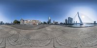 circular panorama photo taken in front of large buildings on a river with a bridge going into the distance