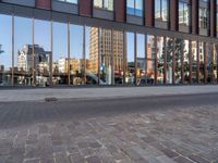 a city street with an empty brick street and glass walls surrounding it and a parked car