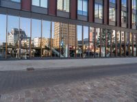 a city street with an empty brick street and glass walls surrounding it and a parked car