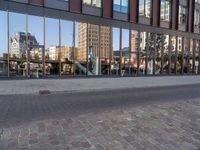 a city street with an empty brick street and glass walls surrounding it and a parked car