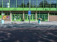 an entrance into an empty building near some bushes and windows to an office area with green walls