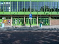 an entrance into an empty building near some bushes and windows to an office area with green walls