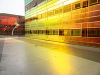 a yellow and green building with many windows reflecting it's sunlight from the window of a nearby building