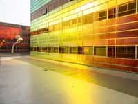 a yellow and green building with many windows reflecting it's sunlight from the window of a nearby building