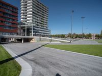 the entrance to a building in a park next to a parking area with cars, and people walking across the street