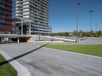 the entrance to a building in a park next to a parking area with cars, and people walking across the street