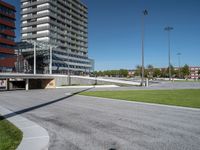 the entrance to a building in a park next to a parking area with cars, and people walking across the street