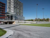 the entrance to a building in a park next to a parking area with cars, and people walking across the street